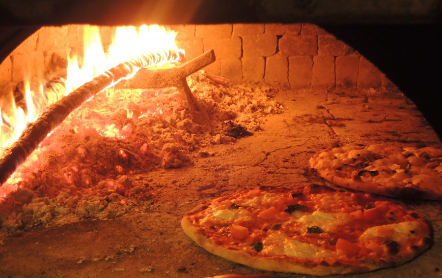 Pizze in cottura davanti alla bocca del forno