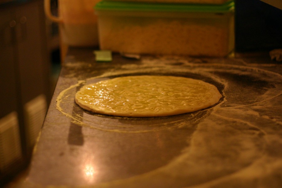 Un disco di impasto steso sul banco della pizzeria